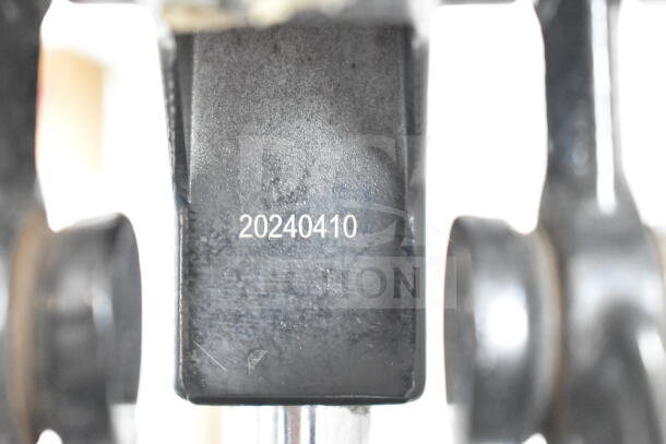 Close-up of a countertop manual juicer with a visible marking "20240410" on a black metal component, indicating model or batch number.