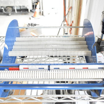 Uline Cutter with blue frame, mounted on a wire shelf. Features multiple cutting rollers, suitable for industrial use.
