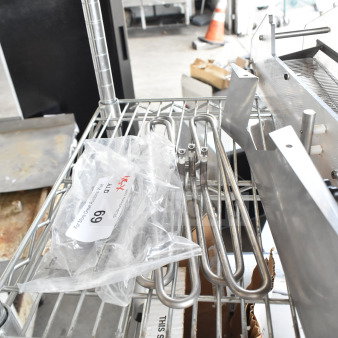 Metal shelving with a ChocoVision Enrober part, heating elements, and a bag labeled "Lot 69 - 5 Times Your Bid!"