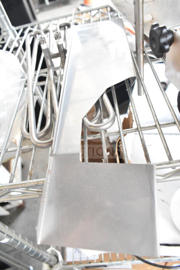 Metal components on a wire rack, part of a ChocoVision Enrober set. Includes various stainless steel parts.