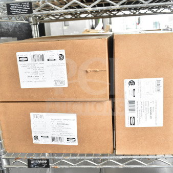 Boxes containing DualLite LED Emergency Light, model EVHC6DP-WM, on a shelf. Labels show specifications and compliance marks.