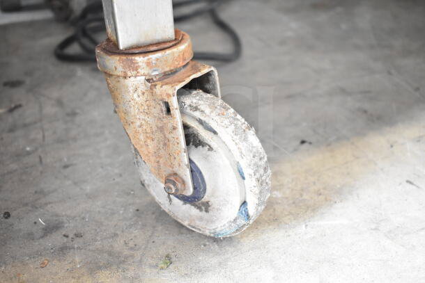 Rusty caster wheel of Henny Penny SCR-6 Rotisserie Oven, showing signs of wear, attached to a metal frame.