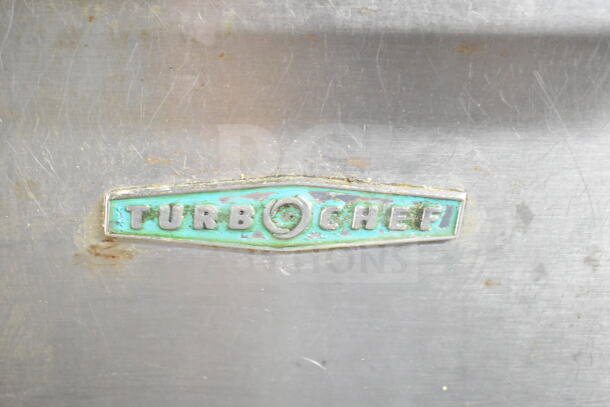 Turbochef NGC logo on the stainless steel surface of a commercial rapid cook oven, showing wear.