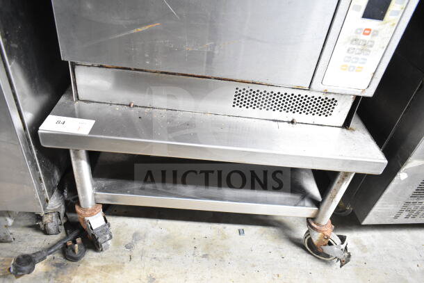 Commercial equipment stand with under shelf on casters; stainless steel, used condition, visible surface wear, tag marked "84".
