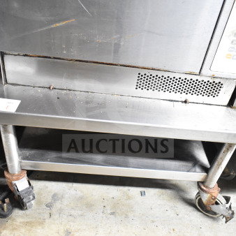 Commercial equipment stand with under shelf on casters; stainless steel, used condition, visible surface wear, tag marked "84".
