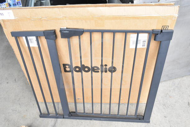 Babelio Baby Gate, black metal, features secure latch, new condition, includes original packaging with visible brand name.