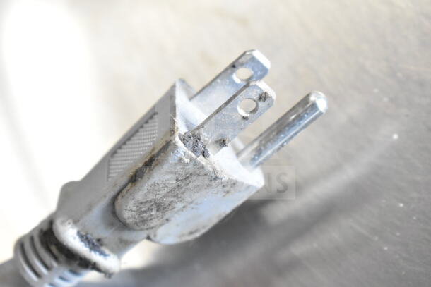 A close-up of a power plug for a 2022 Solwave 180MW112T Commercial Countertop Microwave Oven, showing wear and dirt.