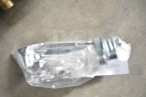 Blurry image of a metal component wrapped in plastic packaging with an attached label. Condition and details unclear.