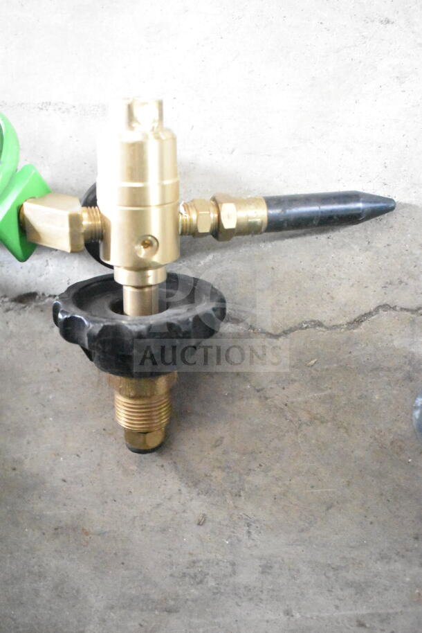 Brass valve assembly with black adjustment knob, metal fittings, and a pointed nozzle, showing some wear.