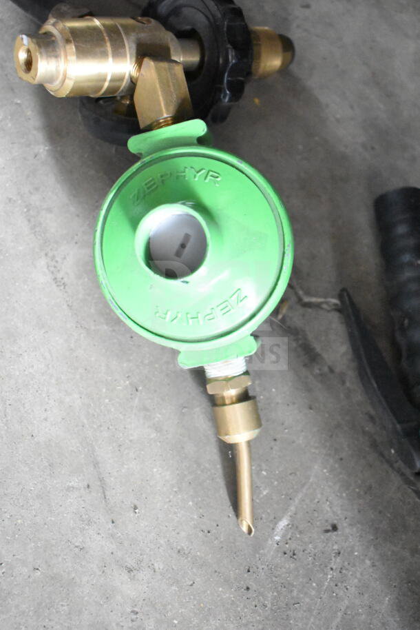Green Zephyr gas regulator with brass fittings, used condition, for propane tanks. Marked "ZEPHYR" on top.