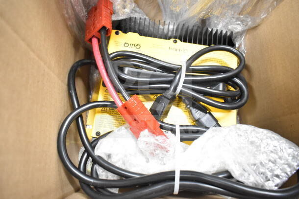 Box containing cables and components for Karcher KM 85/50 R BP 9.841-454.0 ride-on sweeper. Visible labels indicate caution.