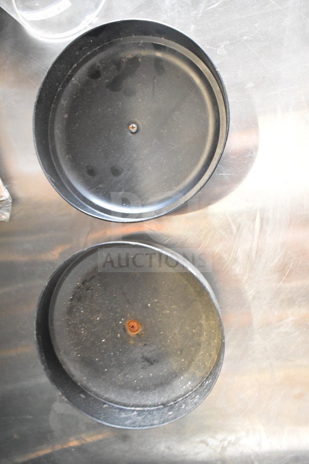 Two black circular metal lids on a metallic surface, part of a lot including Taylor thermometers and a container.