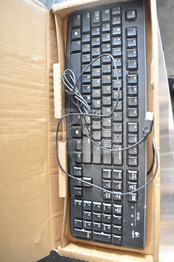 Logitech K120 keyboard in box, visible USB cord. Good condition, some dust present. Auction includes Globe meat slicer blade remover.