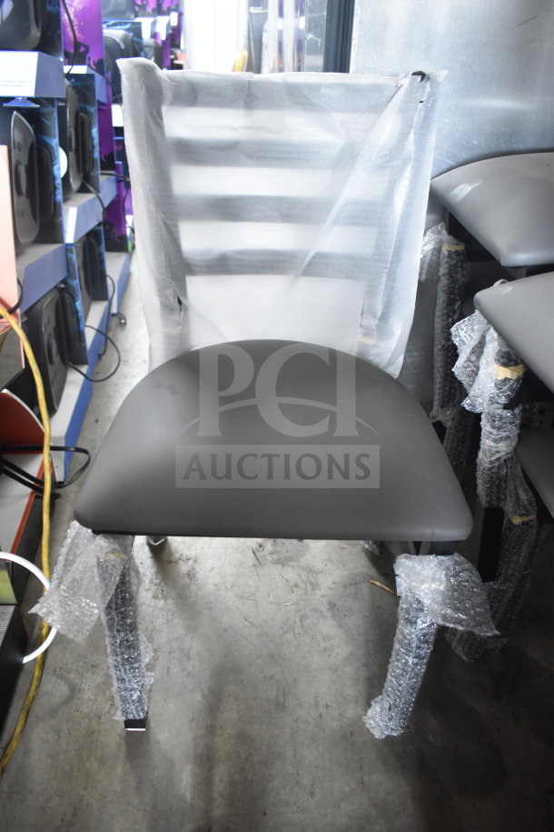 5 brand new Lancaster Table & Seating ladder back chairs, dining height, with dark gray vinyl padded seats, wrapped in protective material.