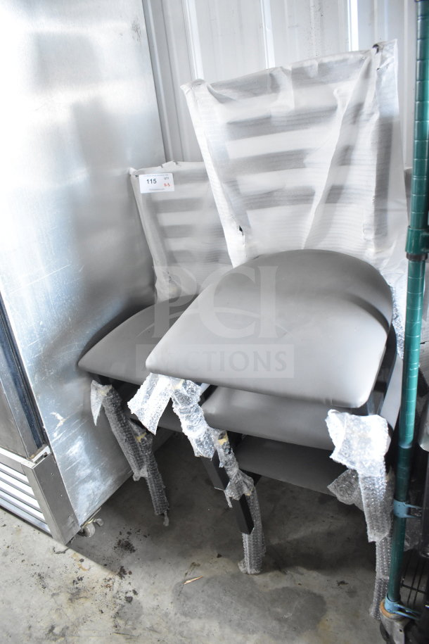 Stack of five brand new Lancaster ladder back dining chairs with dark gray vinyl padded seats, partially wrapped in protective material.