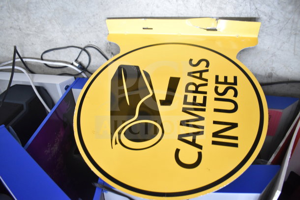 Yellow circular sign with text "Cameras In Use" and camera graphic, slight wear on top edge, auction item.