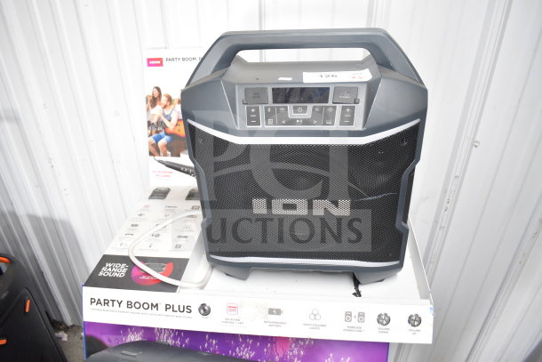 Ion Party Boom Plus Speaker on a store display pedestal. Features include wide-range sound and multi-colored lights.