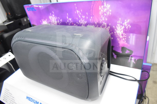 Onn Medium Party Speaker, black, in good condition, on display stand. Speaker features front grille and control knobs.
