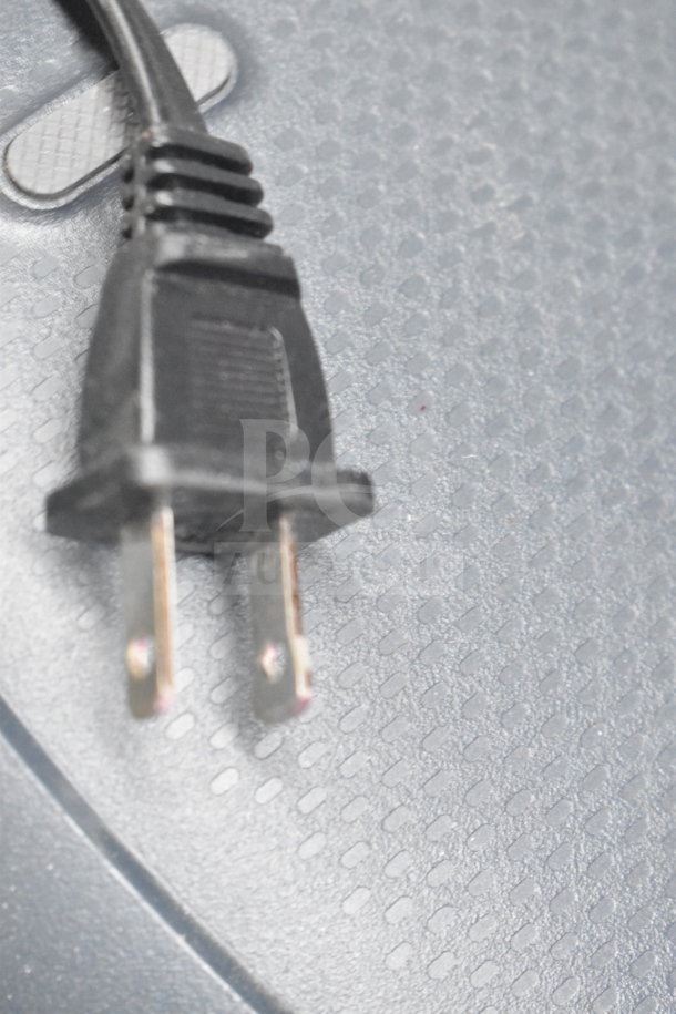 Black power plug on textured grey surface, possibly part of Onn medium party speaker store display set.