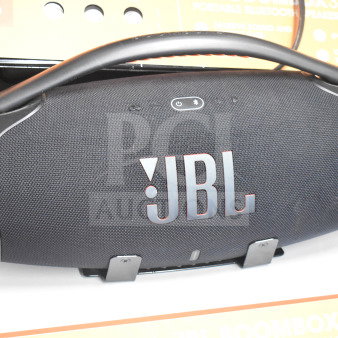 JBL Boombox speaker display, black mesh, sturdy handle, excellent condition, with JBL branding and packaging visible.