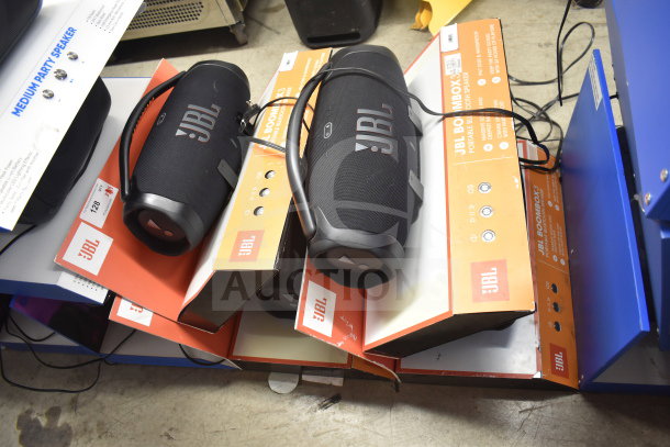 4 JBL Boombox speakers in display boxes, black and orange design, good condition, priced for auction.