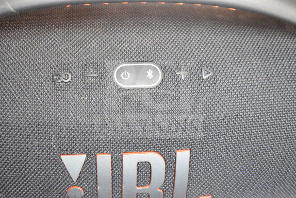 JBL Boombox speaker with control buttons on textured surface, branded logo visible.