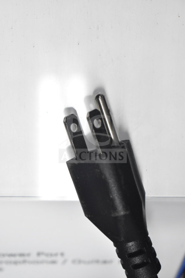 Close-up of a black power plug against a white background. Part of a store display including a Wi-Fi speaker.