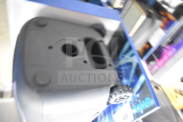 Onn large party speaker on display stand. Features durable wheels and a sturdy handle. Appears in good condition.