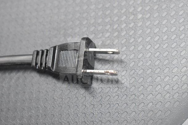 Alt text: Close-up of a black two-prong power plug on a textured surface.