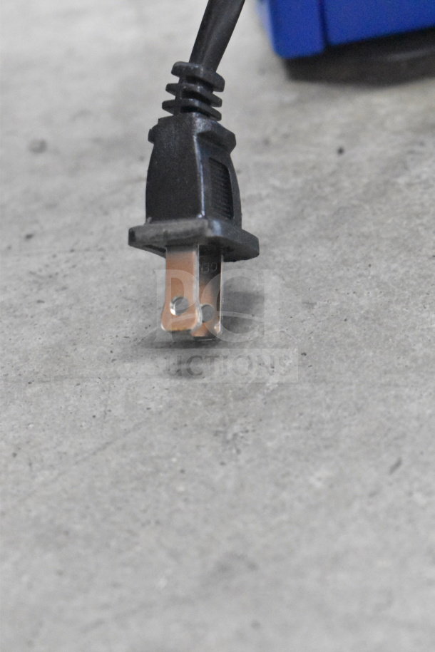 Close-up of a power plug on a gray surface, possibly related to an Onn Medium Party Speaker store display.