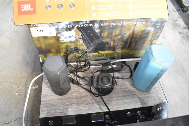 Store display featuring Sony XE200, XB13, and XE300 speakers with set-up cables and promotional background.