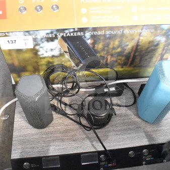 Store display featuring Sony XE200, XB13, and XE300 speakers with set-up cables and promotional background.