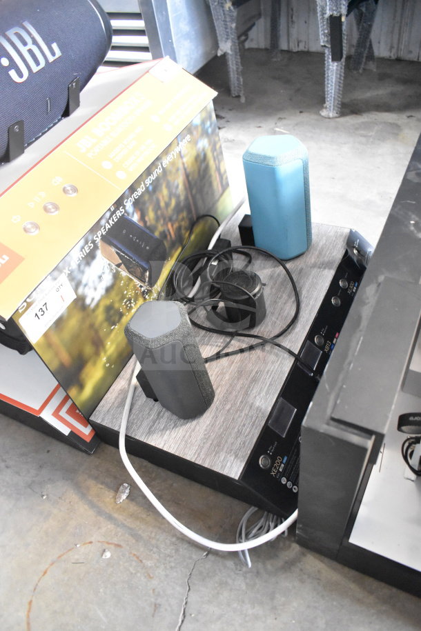 Store display featuring Sony XE200, XB13, and XE300 speakers on a wooden base, showcasing connectivity options.