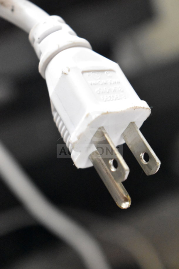White electrical plug with two metal prongs, slightly worn, focus on the prong details.