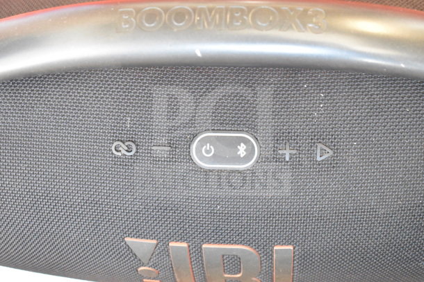 JBL Boombox 3 speaker with control buttons on display, featuring Bluetooth and power symbols.