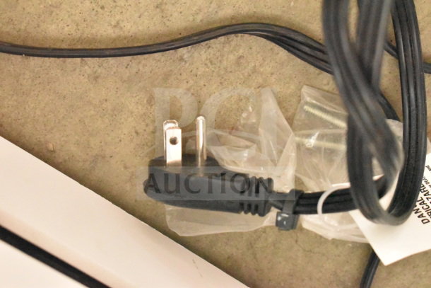 Close-up view of a power cable plug, likely associated with the store display including JBL Boombox 3 Speaker and Soundcore Speaker.