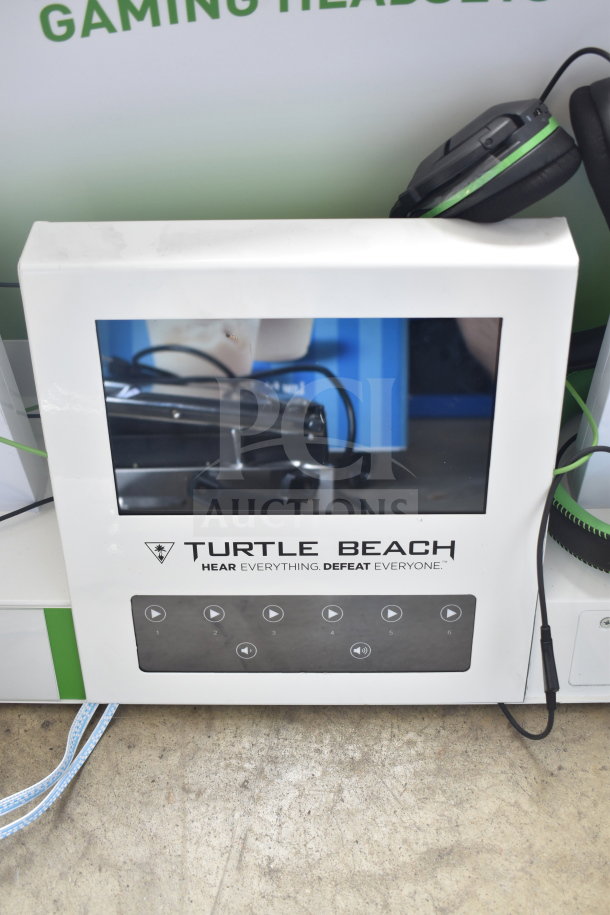 Store display featuring Turtle Beach headphones, white rectangular frame with control buttons, brand logo, and slogan.