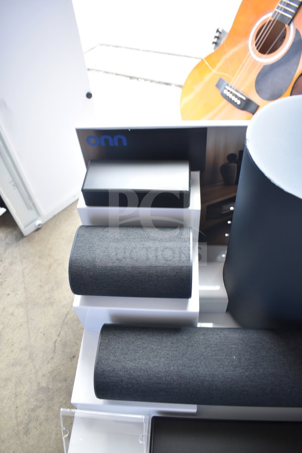 Store display featuring various ONN speakers and soundbar in excellent condition, showcasing sleek black and gray designs.