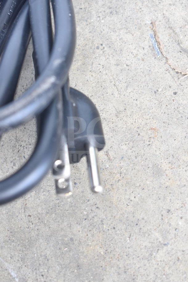 A close-up of a black electrical plug on a gray surface, with no visible speakers or soundbar.