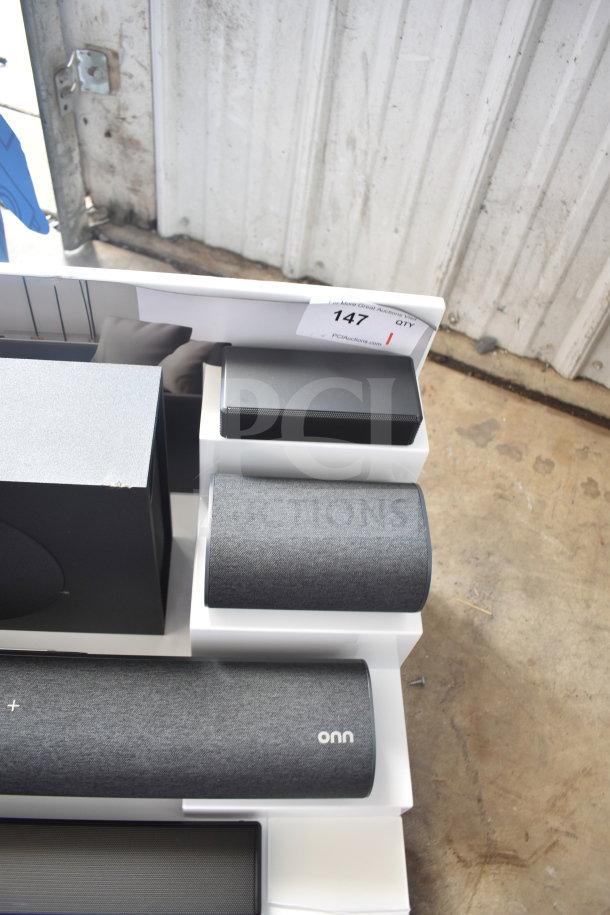 Store display featuring various Onn speakers and a soundbar. Includes product labels and auction tag 147.