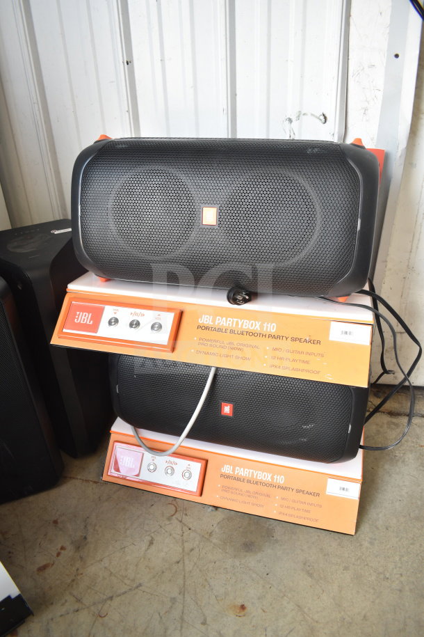 JBL Partybox 110 store display with two speakers, featuring Bluetooth connectivity, dynamic light show, and 12-hour playtime.