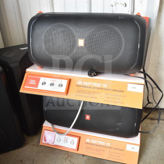 JBL Partybox 110 store display with two speakers, featuring Bluetooth connectivity, dynamic light show, and 12-hour playtime.