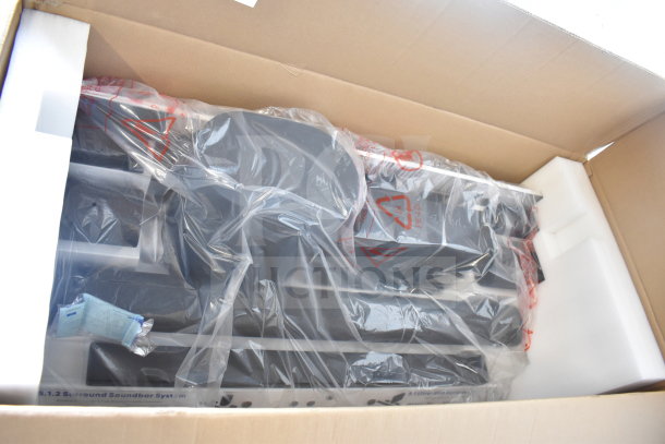 Cardboard box containing Onn speakers and soundbars wrapped in protective plastic. Packaging appears intact and new.