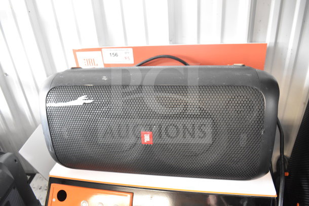 JBL speaker display unit with visible label, positioned on a retail stand. Good condition with minor wear.