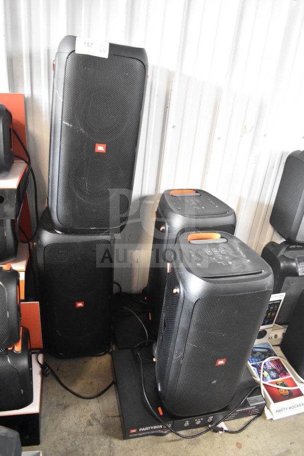 Display of four JBL Partybox 310 speakers, slightly used, with visible control panels and JBL branding, enhancing audio experience.