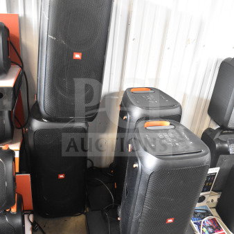 Display of four JBL Partybox 310 speakers, slightly used, with visible control panels and JBL branding, enhancing audio experience.