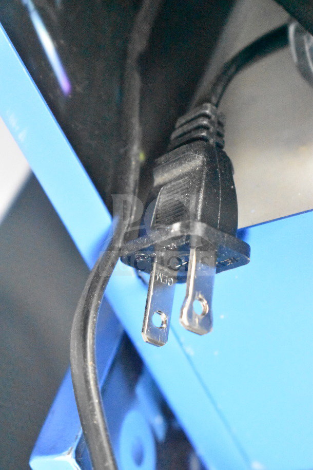 Close-up of a power plug on a blue display stand featuring the Onn Large Party Speaker, part of a 4-store display auction item.