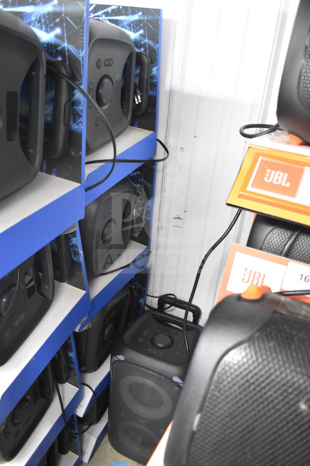 Store display of Onn large party speakers, neatly arranged on blue shelves. Includes visible JBL branding and wiring.