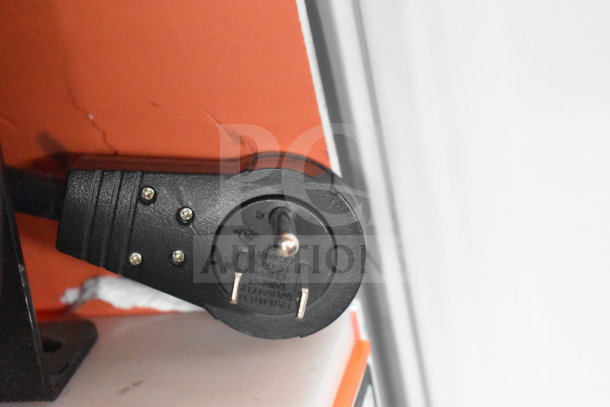 Close-up of a black power plug against a red and white background, associated with JBL Partybox 110 display setup.