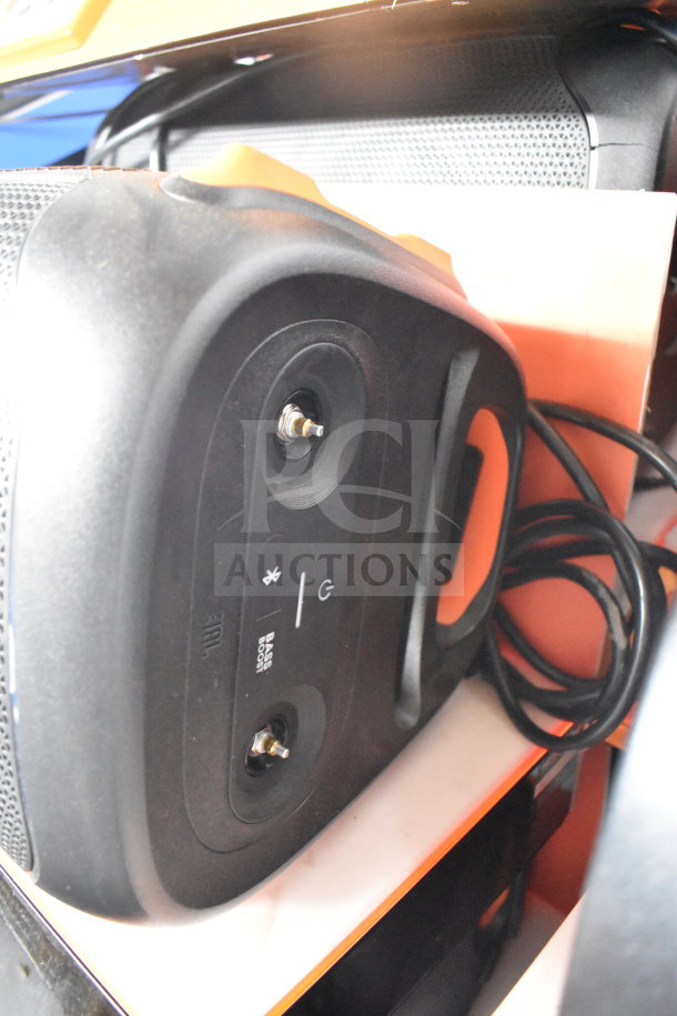 JBL Partybox 110 speaker with Bluetooth and power controls, black casing, visible cord, positioned on a retail display.